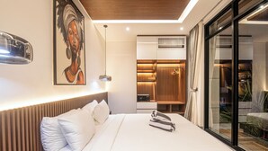 Una habitación de hotel moderna con una cama grande, cabecera de madera, un cuadro en la pared y una puerta corrediza de vidrio que da a un balcón.
