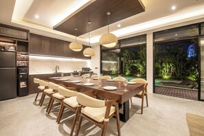 A modern kitchen with a large dining table, multiple chairs, and pendant lights. - Magnificent 5BR Retreat Near Finns Beach Canggu (Canggu)