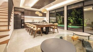 Una cocina moderna con zona de comedor, nevera integrada y un amplio ventanal con vistas a un jardín.