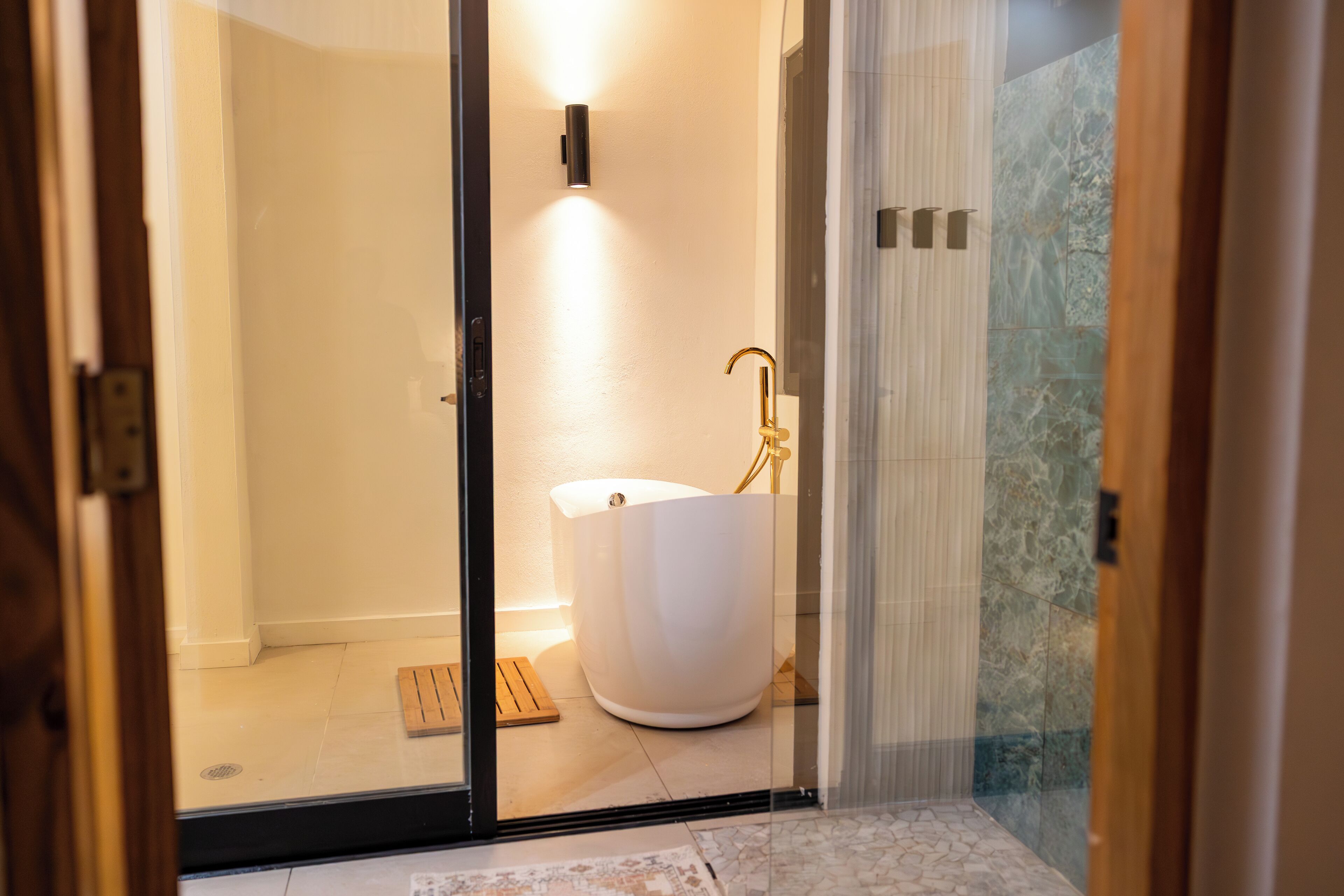 A modern bathroom with a freestanding bathtub, a glass shower enclosure, and a marble-tiled shower area.