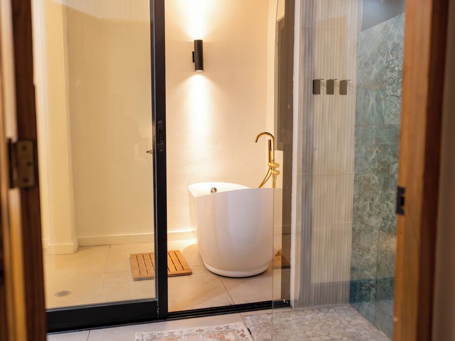 A modern bathroom with a freestanding bathtub, a glass shower enclosure, and a marble-tiled shower area.
