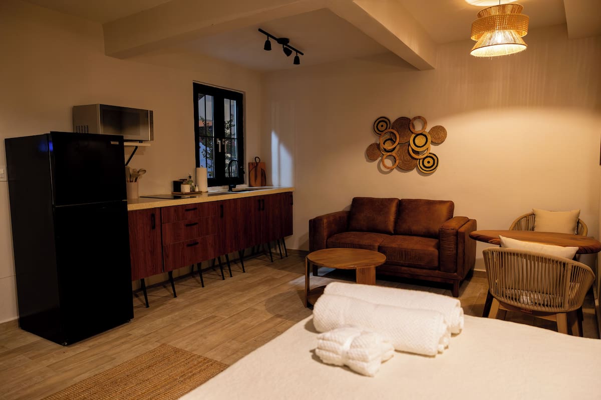 Un espacio habitable compacto con kitchenette, sofá, zona de comedor y cama.