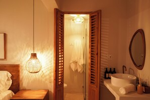 Ein Badezimmer mit Holztür, Waschbecken in Weiß und einem Spiegel.