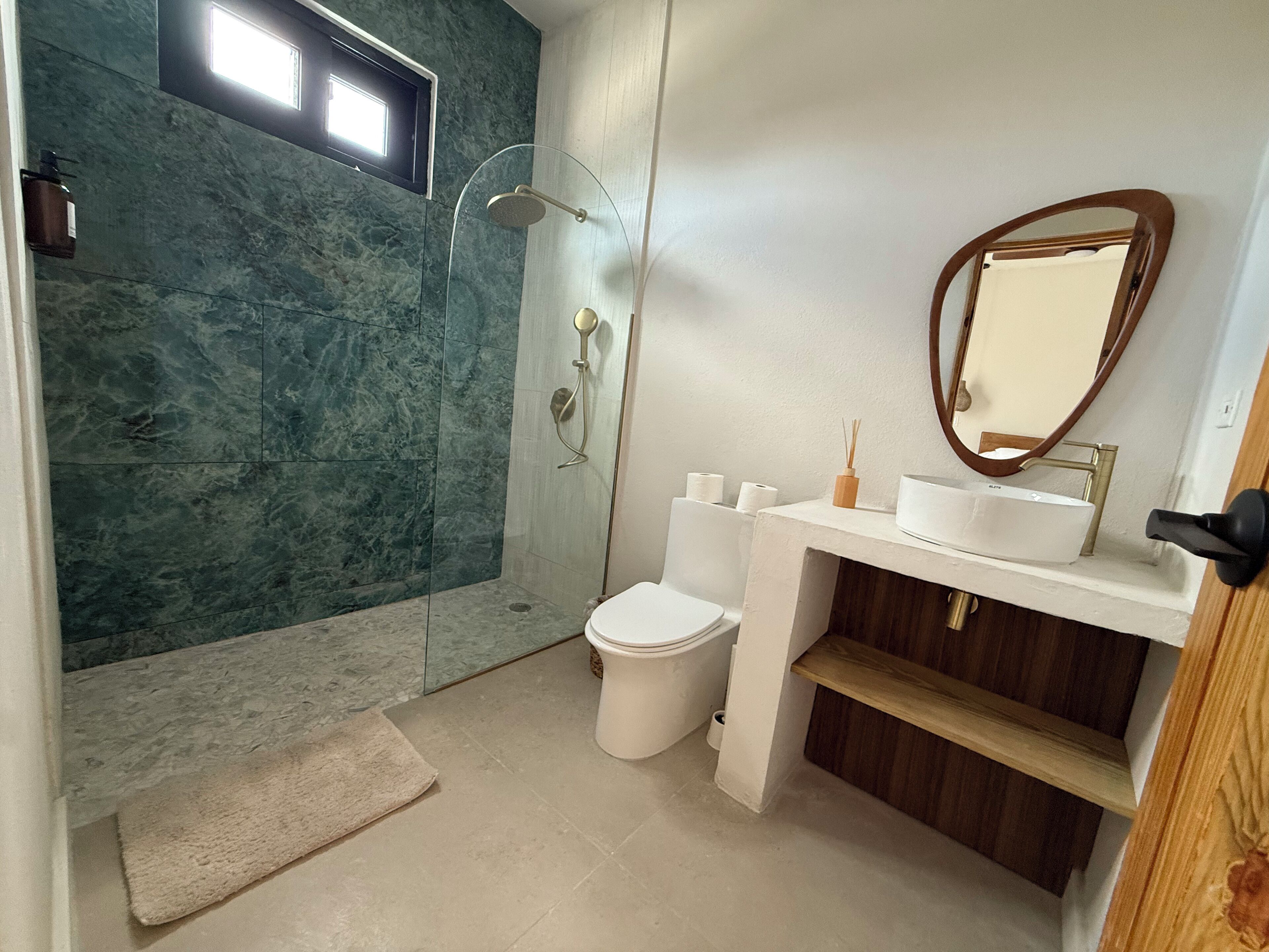 Une salle de bain moderne avec une douche à parois de verre, des toilettes et un lavabo avec un miroir.
