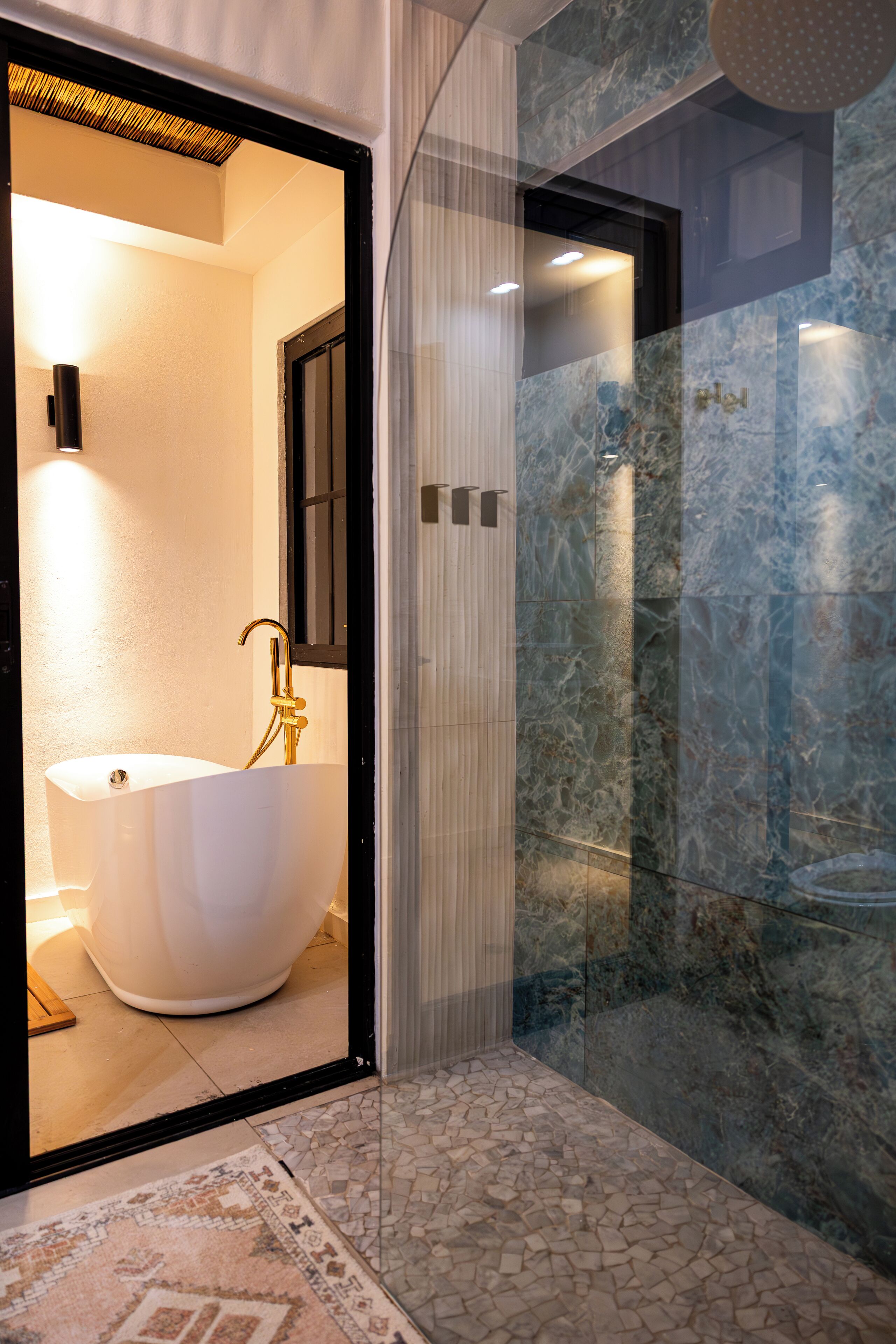 Un baño moderno con una bañera independiente, una ducha con cerramiento de vidrio y suelo de baldosas de mármol.