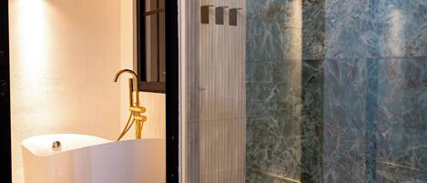 Un baño moderno con una bañera independiente, una ducha con cerramiento de vidrio y suelo de baldosas de mármol.