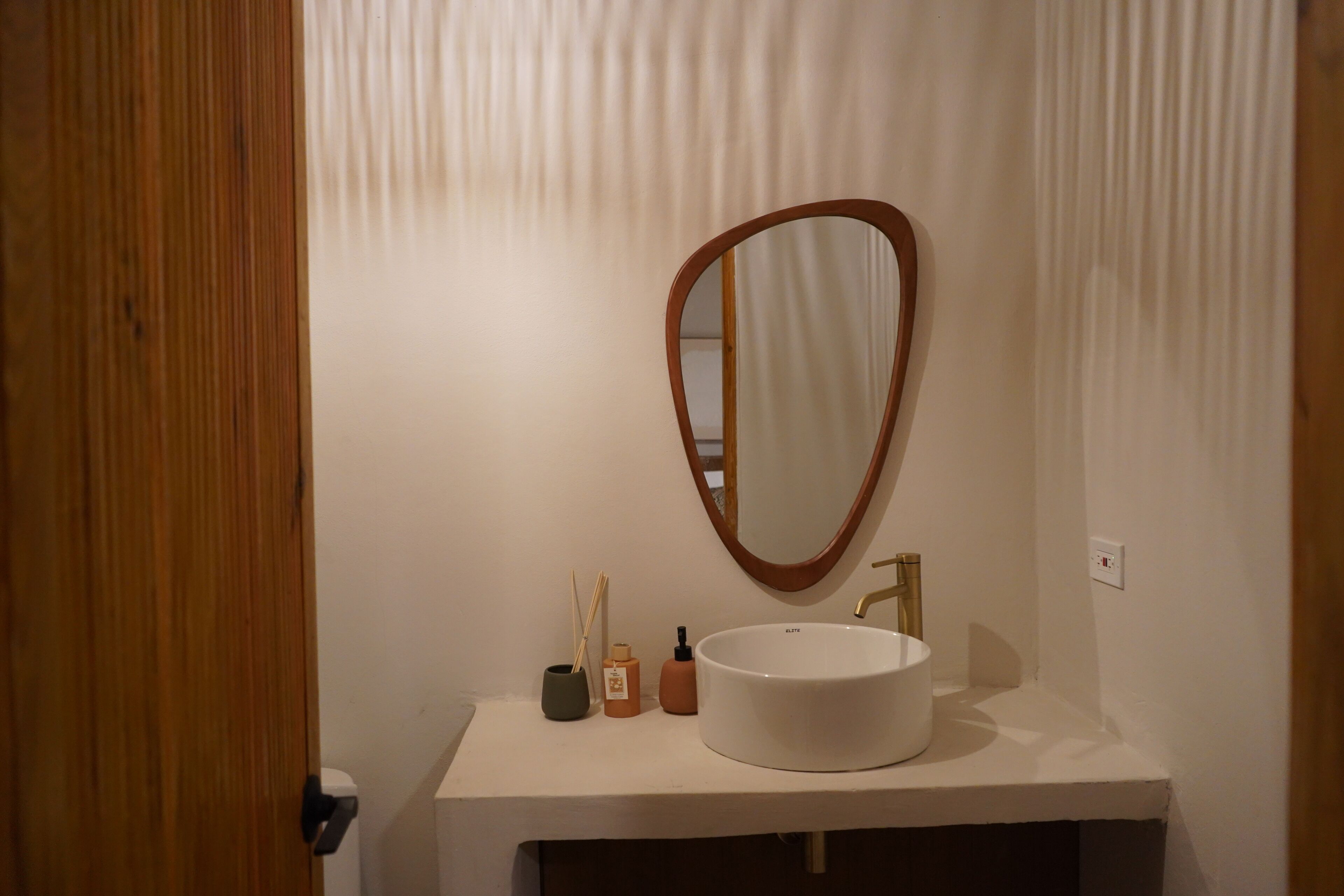 A bathroom with a white sink, a wooden-framed mirror, and a white towel hanging on the wall.