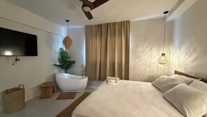 Un dormitorio moderno con una cama grande, un ventilador de techo, un televisor montado, una planta y una lámpara original.