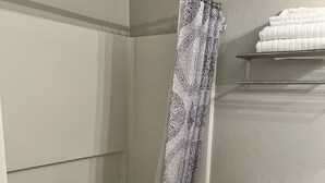 Ein Badezimmer mit Dusche, Toilette und einem Handtuchregal.