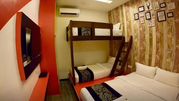 Une chambre avec des lits superposés, un téléviseur et un mur décoré de tableaux encadrés.