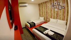 Une chambre d’hôtel avec deux lits, une télévision, un climatiseur et un mur décoré de tableaux encadrés.