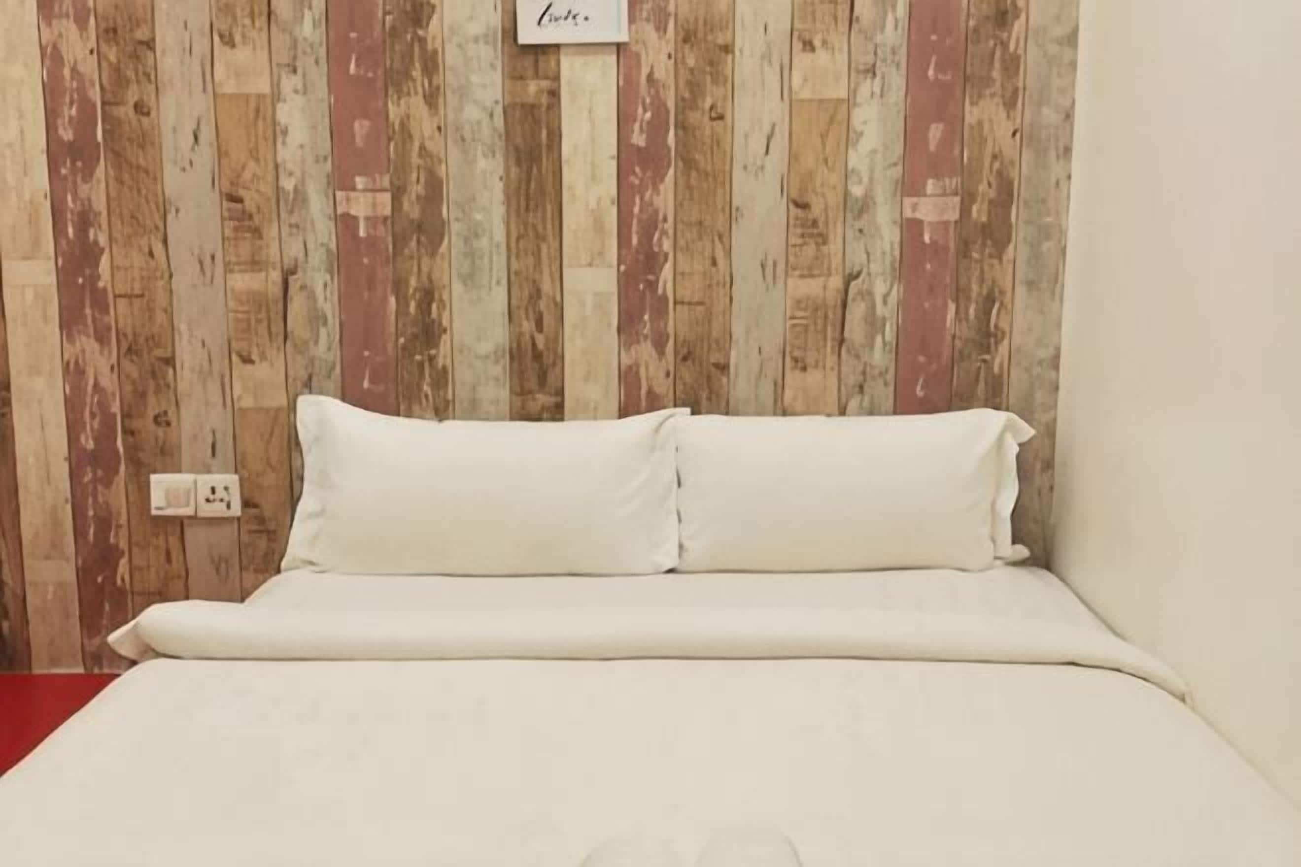 A bed with white bedding in a room with wooden panel walls.