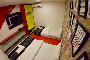 Una habitación con dos camas, televisión, espejo y cuadros en la pared.