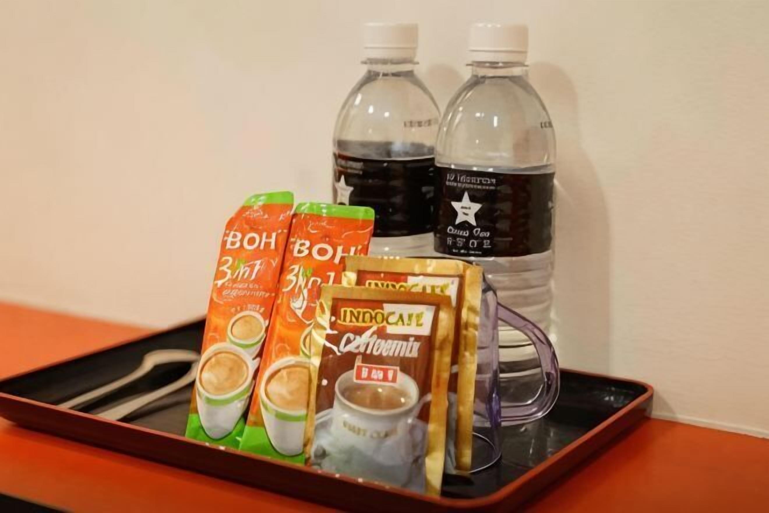 A tray with two bottles of water, two cartons of coffee, and a packet of instant coffee.