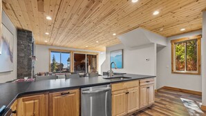 Een moderne keuken met houten kastjes, een RVS vaatwasser en een groot eiland met een spoelbak.