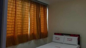 A bedroom with a bed, a window with curtains, a ceiling light, and a small bedside table with a pillow. - WJV INN RAMOS (Cebu City)