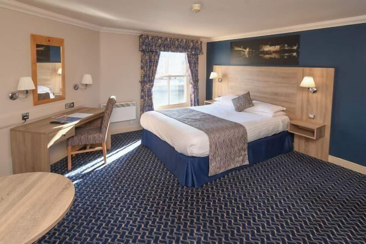 Une chambre d’hôtel avec un lit, un bureau, une chaise et une table ronde.