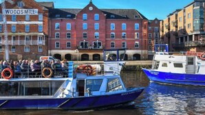Un bateau fluvial était amarré à un quai, et on pouvait apercevoir en arrière-plan un bâtiment historique portant l’inscription « WOODS MILL ».