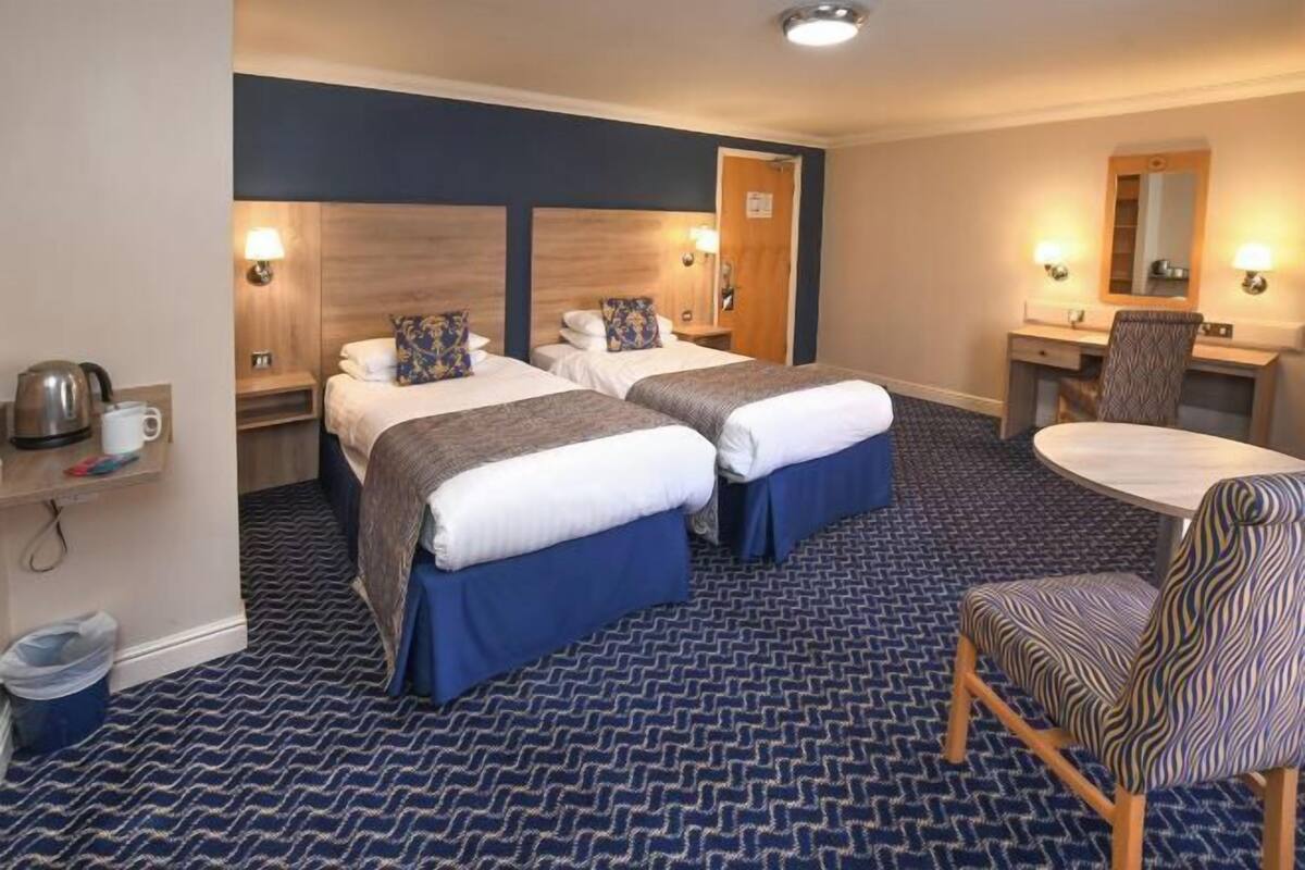 Une chambre d’hôtel avec deux lits, un bureau, une chaise et une petite table.