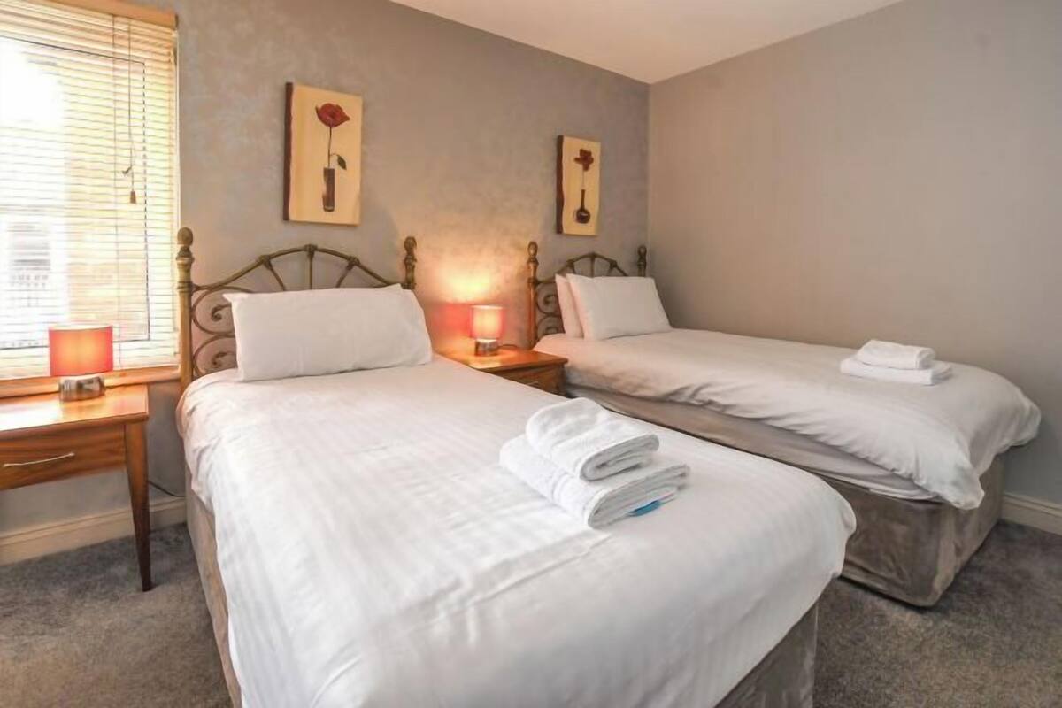 Une chambre d’hôtel avec deux lits, une table de chevet, une lampe et des œuvres d’art accrochées aux murs.