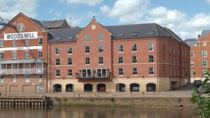 Un grand bâtiment en briques sur lequel on peut lire l’inscription « WOODS MILL QUAY », avec un canal au premier plan.