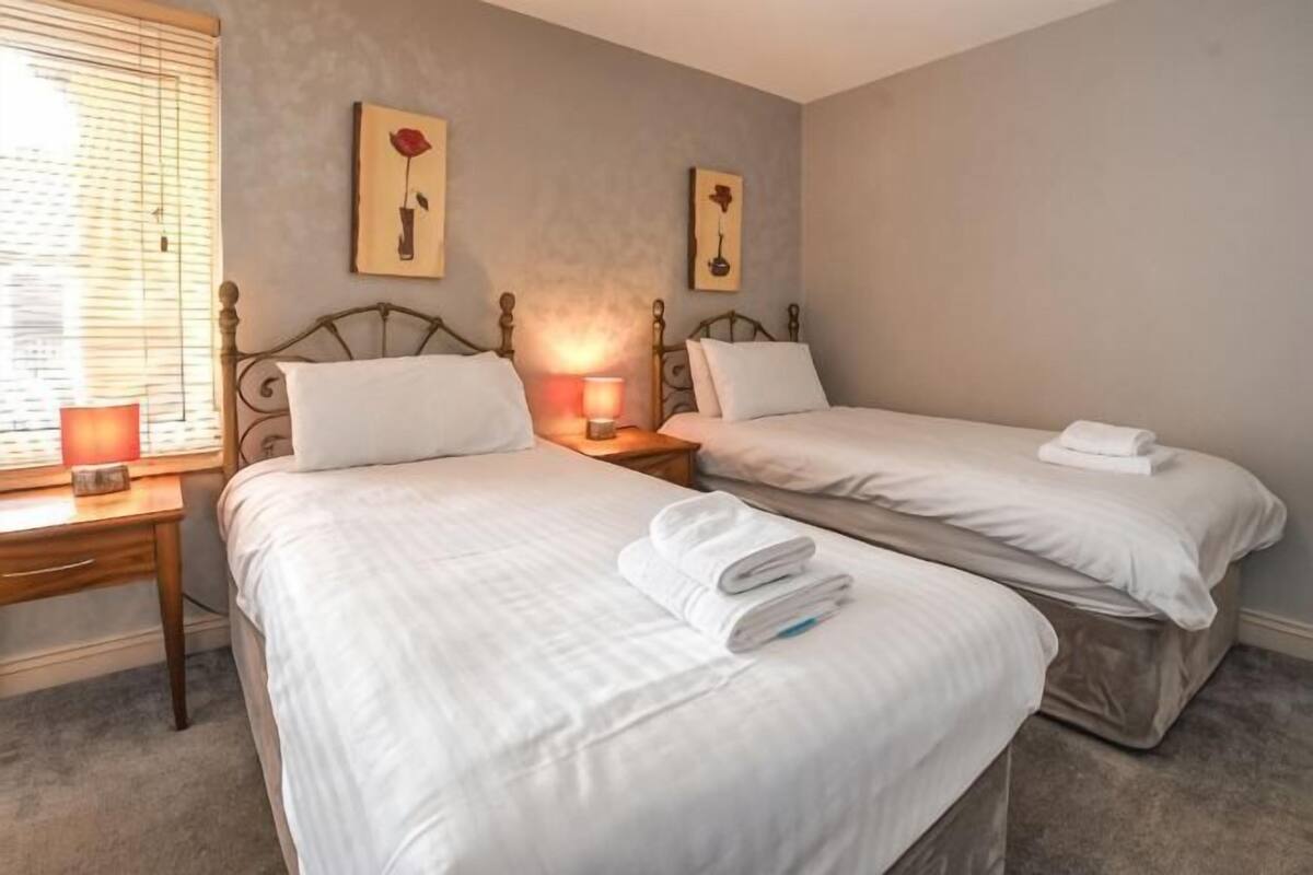 Une chambre avec deux lits, des lampes de chevet et des œuvres d’art accrochées au mur.