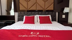 Une chambre d’hôtel avec un lit, une tête de lit et une fenêtre avec des rideaux.