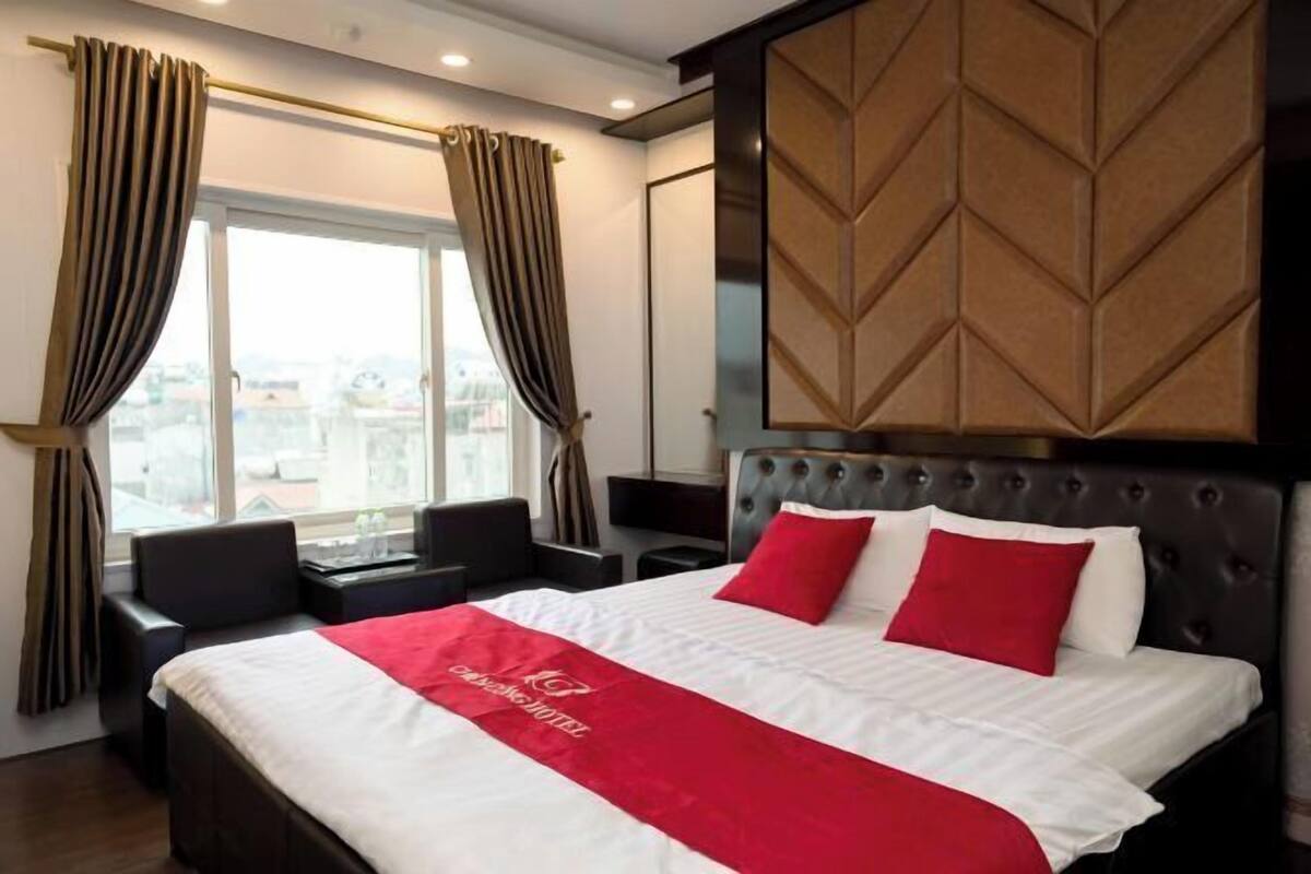 Ein Hotelzimmer mit Bett, Schreibtisch, Stuhl und Blick auf die Stadt.