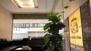 Un hall d’hôtel comprenant un espace salon, une grande plante en pot et un mur sur lequel figure le nom de l’hôtel.