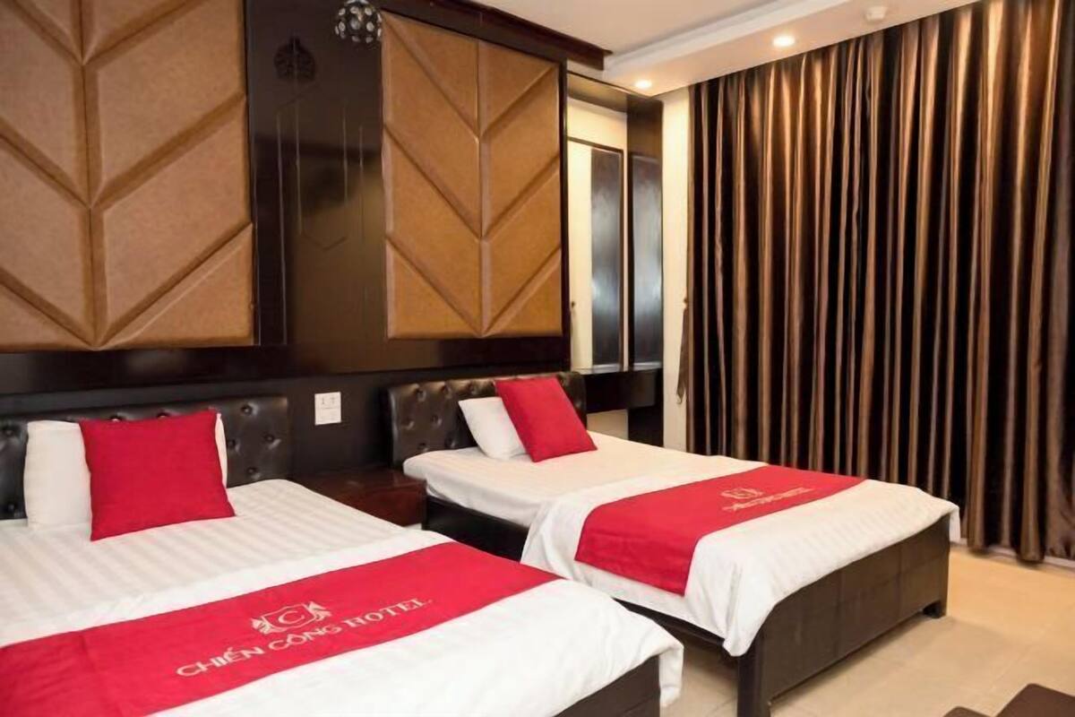 Ein Hotelzimmer mit zwei Betten, jeweils mit einer roten und weißen Bettdecke, einem dunklen Kopfteil und einem großen Spiegel über den Betten.