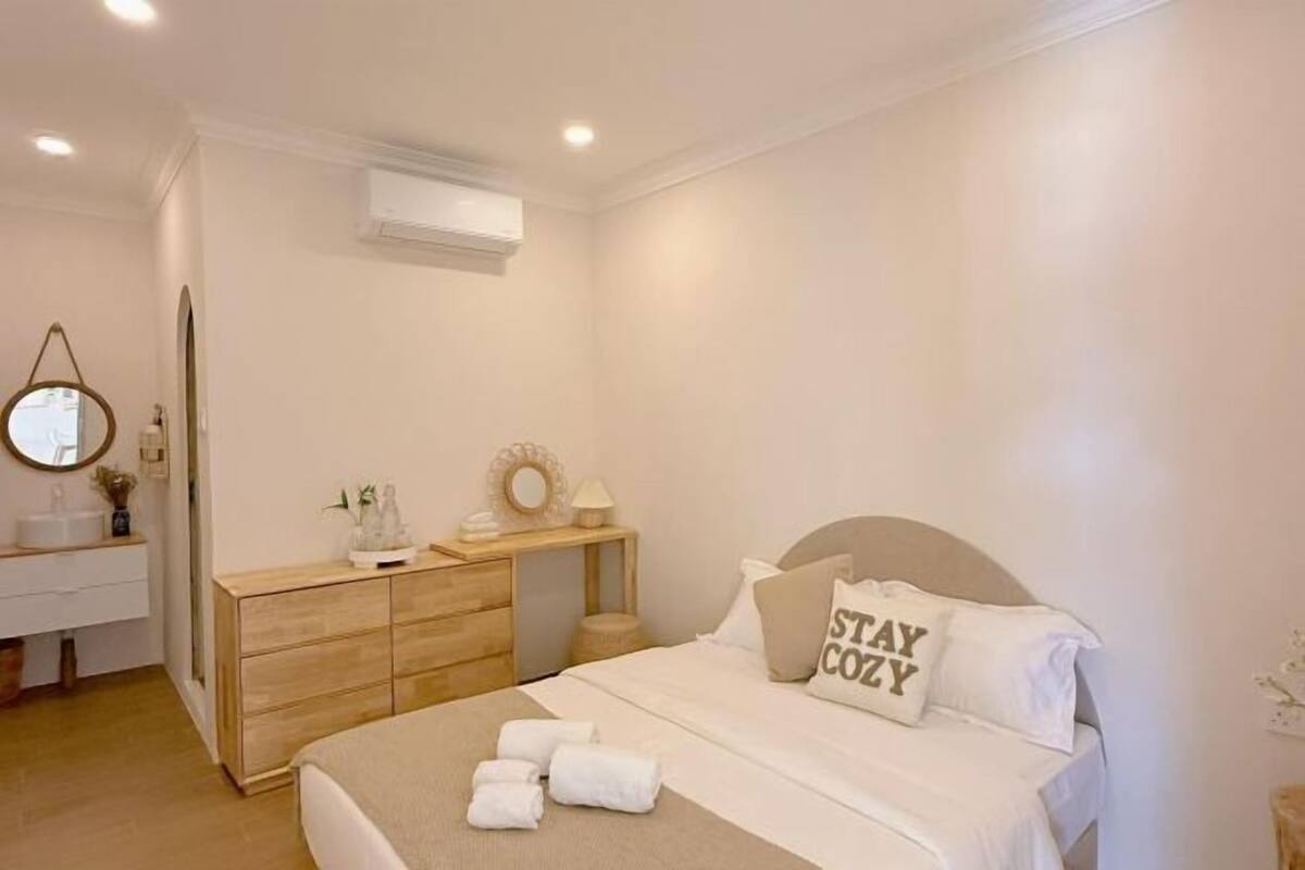 A bedroom with a bed, bedside table, and a dresser.
