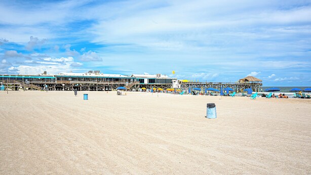 A beach with a pier extending into the water, featuring a restaurant and seating areas. - Steps to Sand: Condo w/ Pool Access in Cocoa Beach (Cocoa Beach)