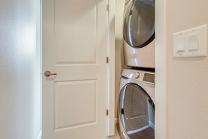 Una sala de lavandería con una puerta cerrada, una lavadora y un secadora apiladas una encima de otra.