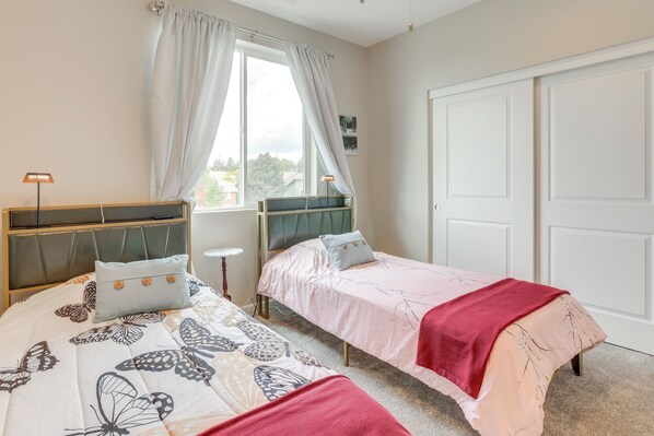 A bedroom with two single beds, a window with curtains, a bedside table with a lamp, and a wardrobe. - Home Base w/ Easy 1-80 Access: 4 Mi to Dtwn Reno! (Reno)