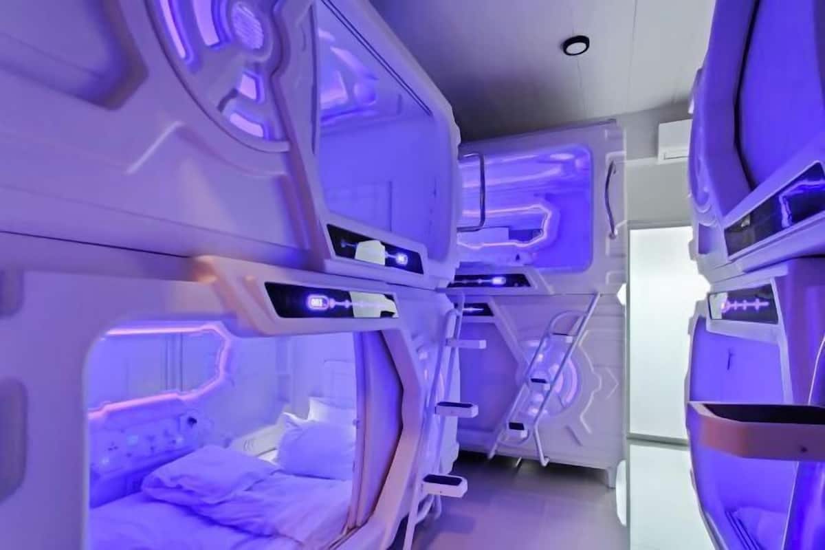 A futuristic room with a central bed and a control panel.