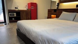 A neatly made bed in a hotel room with a microwave and a red appliance on the countertop. - Dodu trophycal Pool Villa near by Airport (Jeju)