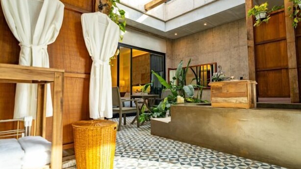 A hotel room with a bed, a wooden bench, a wicker basket, and a reception desk. - Dodu trophycal Pool Villa near by Airport (Jeju)
