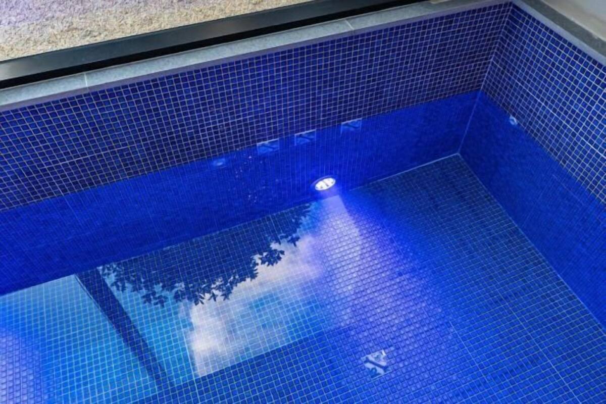 Ein Schwimmbecken mit blauen Fliesen und einem sichtbaren Ablass.