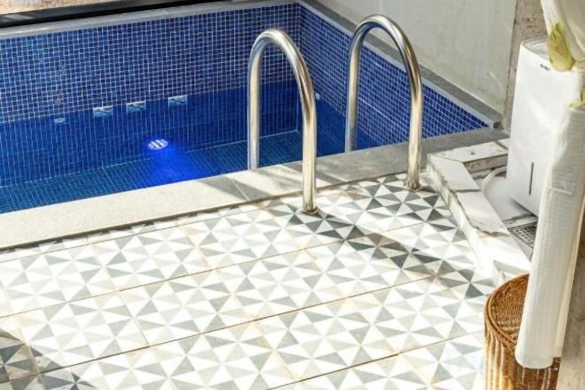A swimming pool with a geometric tile pattern and metal handrails.