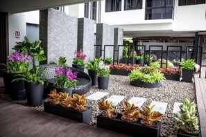 A courtyard with potted plants, a seating area, and a building in the background. - Escape Condominium Beachfront Suites - Mae Phim (Klaeng)