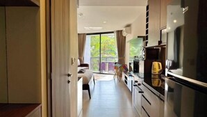 Eine moderne Küche mit Kühlschrank, Mikrowelle und Herd, die auf einen Balkon mit Blick auf Grünflächen führt.