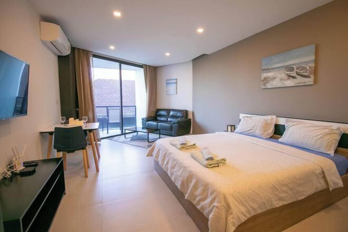 A hotel room with a bed, a desk, a chair, a TV, and a balcony.