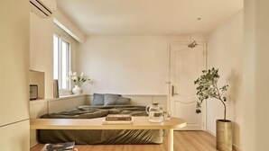 Habitació compacta amb llit, taula de nit i una planta en test.