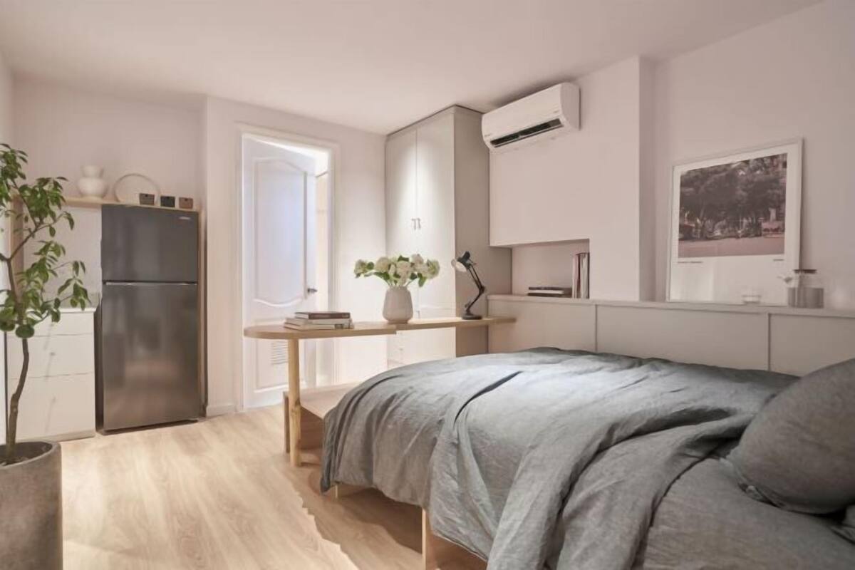 Un dormitorio moderno con cama, mesita de noche y ventana.