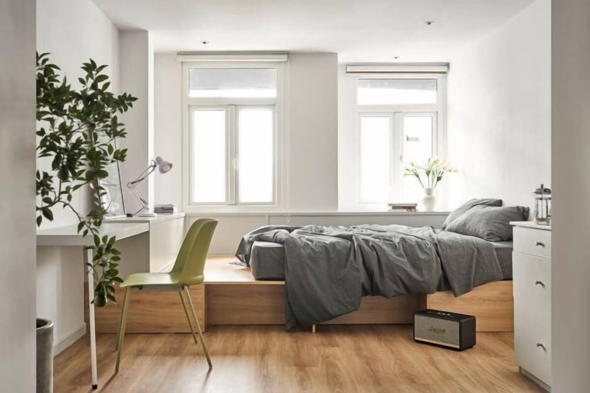 Un dormitorio pequeño con cama, escritorio, silla y ventana.