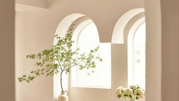 Una habitació amb finestres d'arc, una planta en test i un ram de flors.
