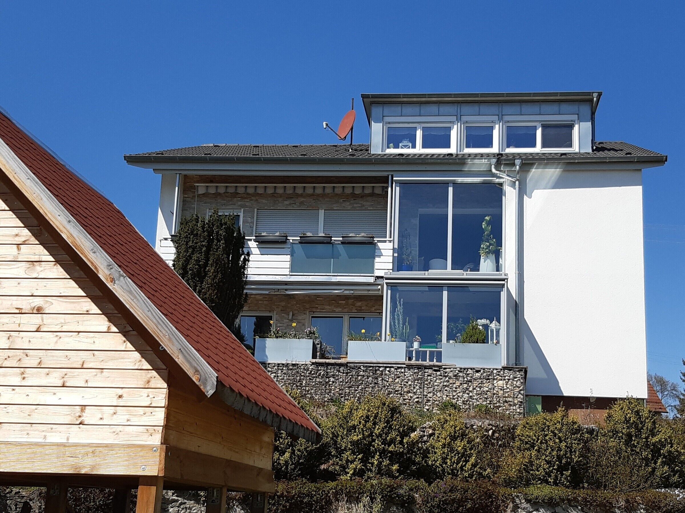 En byggnad med flera våningar, ett sluttande tak, stora fönster och en flagga.