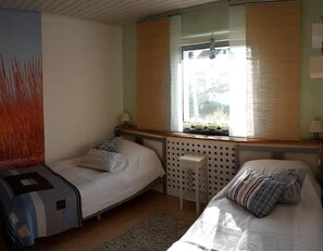 A bedroom with two single beds, a window with blinds, a radiator, and a wall-mounted shelf. - Apartment 'Städtle-Blick' with Shared Garden, Balcony and Wi-Fi (Hayingen)