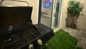 Una parrilla, una puerta corrediza de vidrio y una planta en maceta.