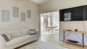 A living room with a sofa, a TV mounted on the wall, a dining area with a table and chairs, and a kitchen area with a counter and cabinets. - < 4 Mi to UAB & Dtwn: Updated Birmingham Apt (Birmingham)